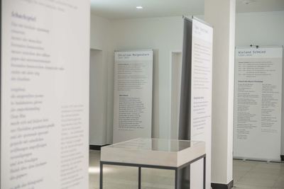 Blick zwischen mehreren Texttafeln mit Schachgedichten und Dichterbiografien hindurch, in der Mitte eine Glasvitrine.