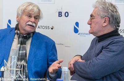 Interview für die Liveübertragung: Gast im blauen Sakko spricht, sein Gegenüber im Rollkragen hört zu