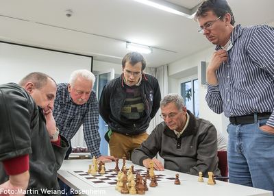 Nach der Runde: mehrere Spieler stehen um ein Brett und analysieren gemeinsam die Stellung