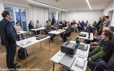 Siegerehrung: ein Mann im Sakko spricht stehend zu den im Saal versammelten Turnierteilnehmern