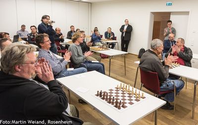Applaus im Turniersaal zum Abschluss des Schach960-Festivals, vorn ein Brett mit aufgebauten Figuren
