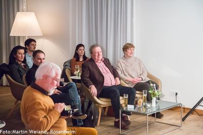 Publikum in Sesseln verfolgt beim Poetry Slam zum Thema Schach aufmerksam die Bühne; im Vordergrund ein Mann mit Kamera.