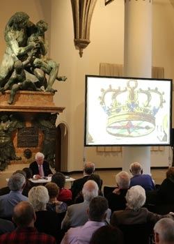 Vortrag im Bayerischen Nationalmuseum: Zuhörer vor einer Leinwand mit einer Kronen-Abbildung, links ein großes Bronzedenkmal