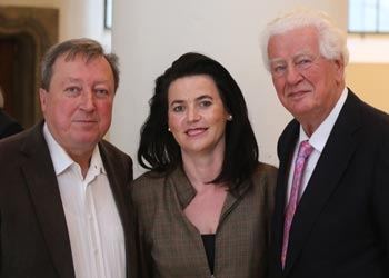 Zwei Herren und eine Frau in der Mitte posieren lächelnd für ein Erinnerungsfoto beim Sammlertreffen