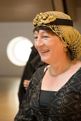 Frau im schwarzen, golden bestickten Kleid mit goldenem Haarnetz und Kronenschmuck – Kostüm einer schwarzen Dame