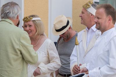 Weiße Dame und weißer König mit goldenem Kopfschmuck plaudern vor Beginn der Aufführung mit Gästen