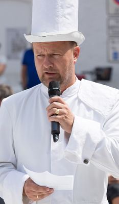 Redner im weißen Turmkostüm mit hohem Zylinder liest mit Mikrofon in der Hand vom Blatt ab