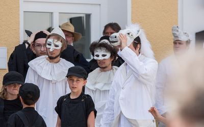 Weiße Bauern mit Halskrausen und Halbmasken, ein Springer mit Pferdekopf und schwarze Bauern in Latzhosen warten auf ihren Einsatz