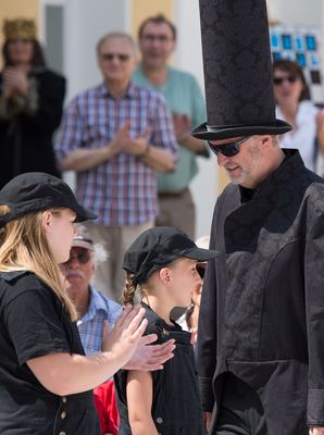 Schwarzer Läufer mit hohem dunklem Hut und Sonnenbrille zieht an den schwarzen Bauern vorbei, Zuschauer applaudieren