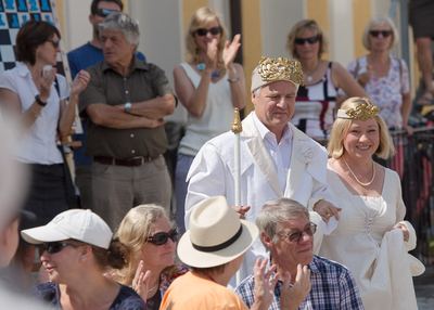 Weißer König mit Krone und Zepter und die weiße Dame mit Diadem schreiten durch das applaudierende Publikum