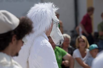 Weißer Springer mit zotteligem Pferdekopf aus Pappmaché auf dem Spielfeld, im Hintergrund sitzende Zuschauer