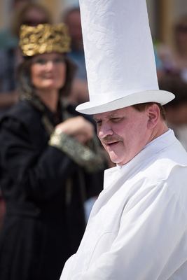 Weißer Turm mit hohem Hut blickt zur Seite, im Hintergrund unscharf der schwarze König mit Goldkrone