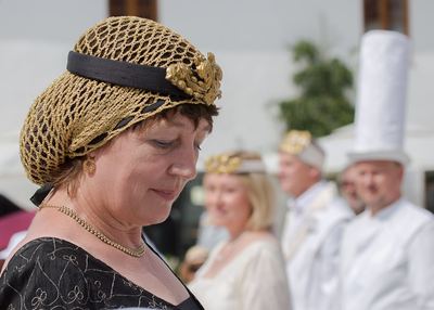 Schwarze Dame mit goldenem Haarnetz blickt nach unten, dahinter unscharf das weiße Königspaar und ein weißer Turm