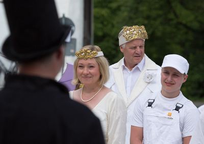 Weißes Königspaar mit goldenem Kopfschmuck und ein weißer Bauer mit Kappe blicken auf einen schwarzen Läufer