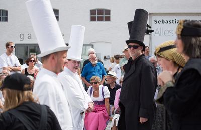 Zwei weiße Türme, ein schwarzer Läufer und die schwarzen Damen stehen auf dem Spielfeld vor dichtem Publikum