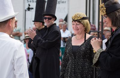 Schwarzer Läufer applaudiert, die schwarze Dame lächelt einem weißen Turm zu, rechts der schwarze König