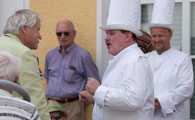Großmeister im hellgrünen Sakko im lockeren Gespräch mit zwei weißen Türmen nach dem Spiel