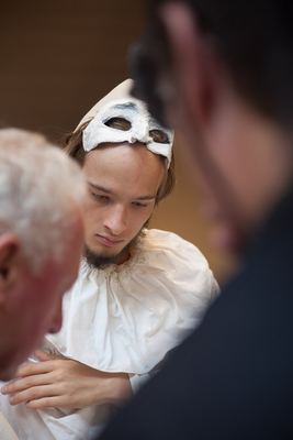 Junger weißer Bauer mit hochgeschobener Halbmaske und Halskrause blickt konzentriert nach unten