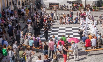 Luftblick auf den Hof: Alle 32 lebenden Figuren stehen in Grundstellung am großen Schachbrett, ringsum Publikum