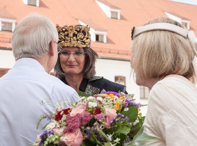 Schwarzer König mit Goldkrone im Gespräch mit einem Gast, vorn ein bunter Blumenstrauß der weißen Dame
