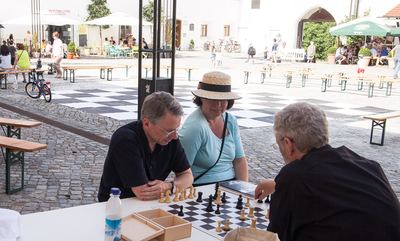 Freie Partie am Tisch im Hof, im Hintergrund das leere Schachfeld und Bierbänke