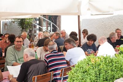 Gut besetzte Tische im schattigen Biergarten beim Ausklang des Jubiläumsnachmittags
