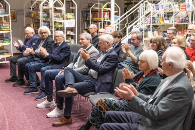 Applaudierendes Publikum in den vorderen Stuhlreihen der Stadtbücherei, im Hintergrund Regale mit Spielen und Büchern