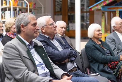 Zuhörer in der ersten Reihe, darunter ein Mann im Trachtenjanker und einer mit verschränkten Armen, lauschen der Rede