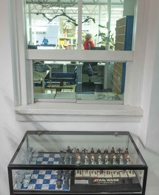 Glasvitrine mit Schachspielen aus „Harry Potter“ und „Star Wars Episode I“, darüber ein Fenster mit dem Ausstellungskatalog