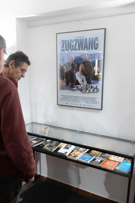 Besucher an einer Vitrine mit verfilmten Schachromanen wie „The Queen’s Gambit“, darüber das Tatort-Plakat „Zugzwang“