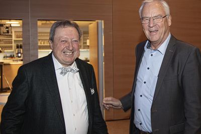 Zwei lachende Gäste im Foyer des Bürgerhauses, einer mit schachbrettgemusterter Fliege