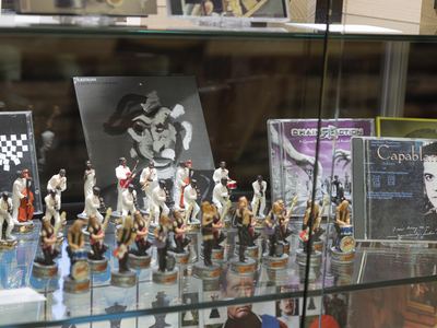 Schachspiel mit Musikerfiguren in einer Vitrine: weiß gekleidete Jazzband gegen Rockmusiker mit Gitarren, dahinter CD-Hüllen
