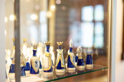 Porzellan-Schachfiguren in Kobaltblau, Weiß und Gold mit Kronen und Mitren auf dem Glasboden einer Vitrine