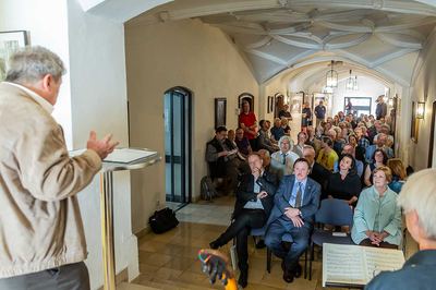 Blick über die Schulter eines Redners am Stehpult auf das Publikum, das den gewölbten Gang des Ebersberger Rathauses füllt