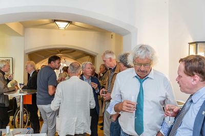 Gäste im Gespräch beim Empfang mit Weingläsern in den Händen, im Hintergrund der gewölbte Rathausgang