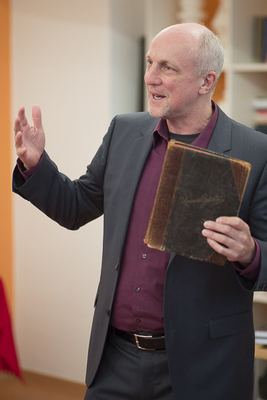Redner mit dem alten Gästebuch in der einen Hand gestikuliert lebhaft mit der anderen