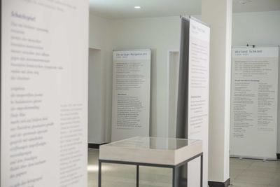 Mehrere Roll-up-Texttafeln mit Dichterbiografien und Schachgedichten stehen im hellen Ausstellungsraum um eine Vitrine.