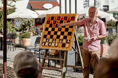 Großmeister zeigt am Demobrett auf eine Figur und erläutert die Spanische Partie
