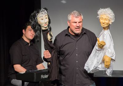 Sänger zwischen der gekrönten schwarzen und der weißhaarigen Puppe, dahinter der Pianist am Keyboard