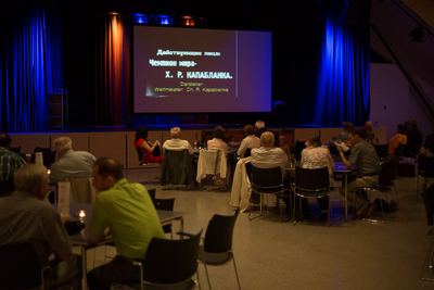 Filmvorführung im abgedunkelten Saal: Auf der Leinwand der russische Zwischentitel eines Stummfilms mit deutscher Darstellerangabe