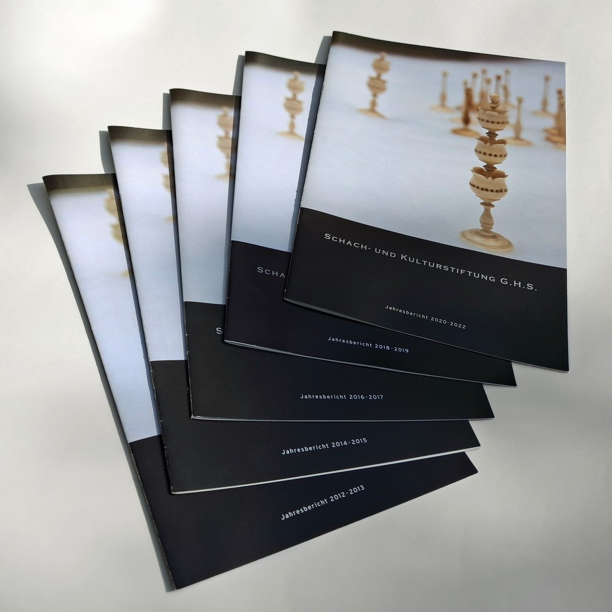 Fünf aufgefächerte Jahresberichte der Schach- und Kulturstiftung G.H.S. von 2012–2013 bis 2020–2022, auf dem Umschlag eine historische Schachfigur